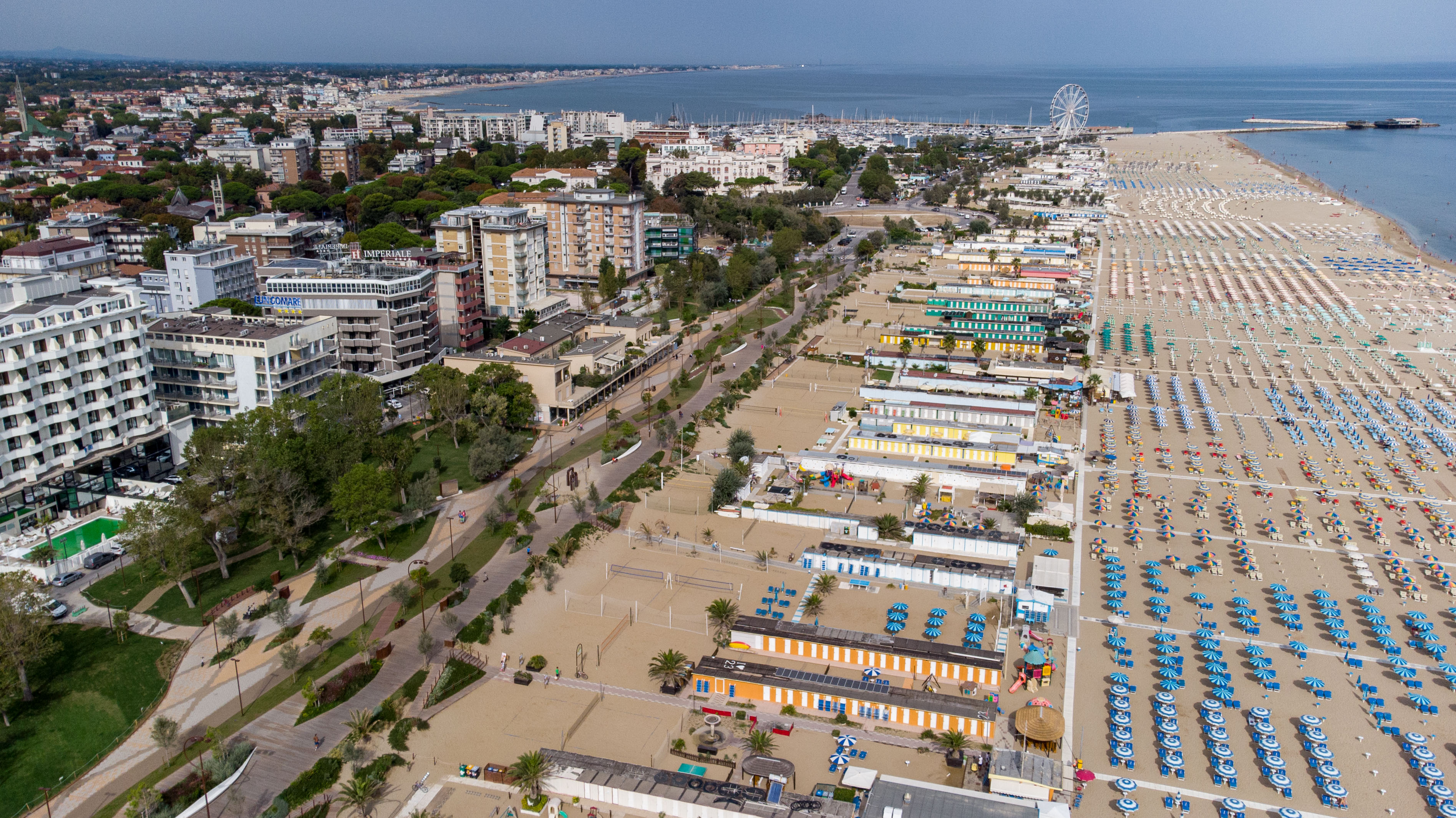 A picture from above of Rimini and its 'Parco del Mare'. it show urban buildings, and then a green line inbetween the beach and those buildings.