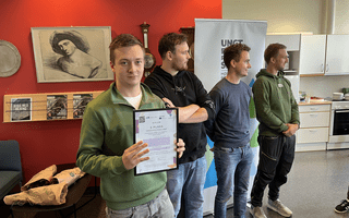 Four young people with the person in front holding up a diploma, presumingly for having had the best idea.