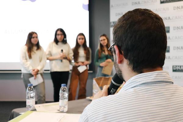 A group of people can be seen on stage in the background, seemingly receiving feedback